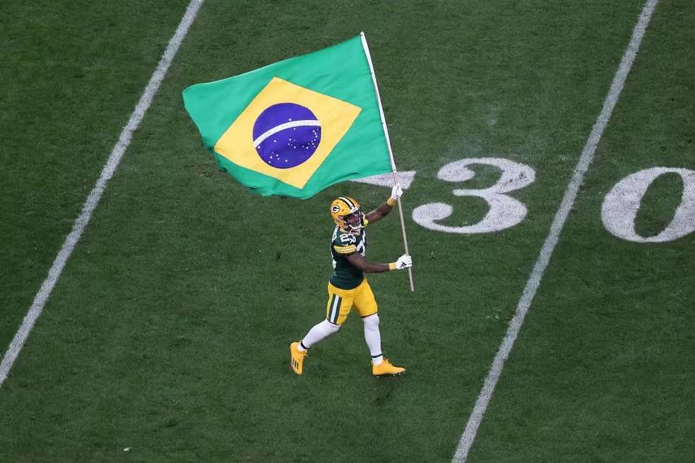 Crédito: NFL Brasil - Jaire Alexander, dos Packers, entra em campo com a bandeira do Brasil — Foto: Wagner Meier/Getty Images